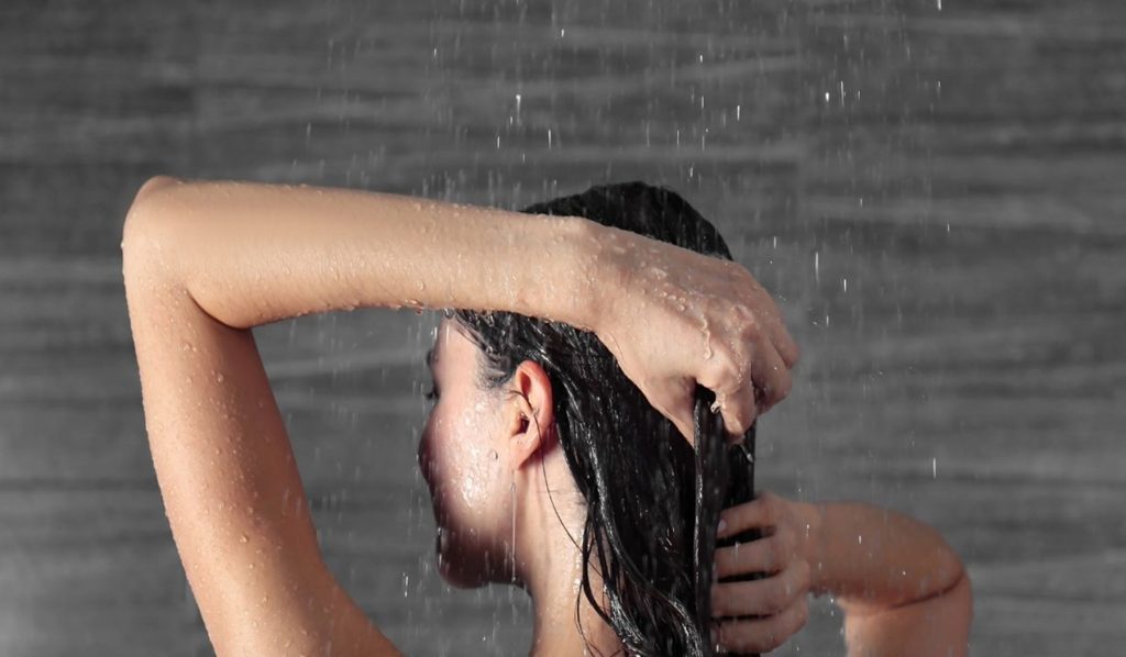 Lady showering using a water saving shower head.